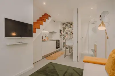 a white living room with a staircase and a tv at Nature Cosy Private House,w/AC Downtown near Metro in Porto