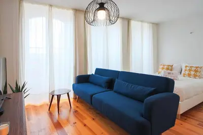 a living room with a blue couch and a bed at HM – Historic Downtown Batalha Studio in Porto