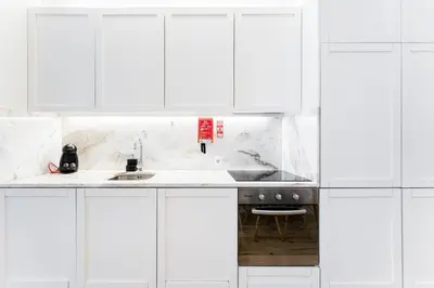 a white kitchen with white cabinets and a sink at HiddenGem - Cherry on Top in Porto
