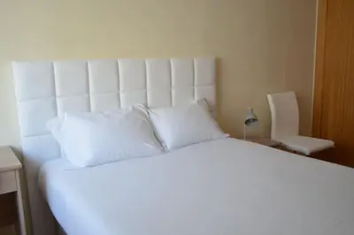 a large white bed with white pillows in a bedroom at Sense Porto in Porto