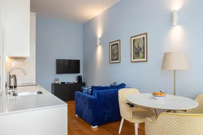 a kitchen and living room with a table and a blue couch at CASA JOY Santa Catarina apartment in Porto