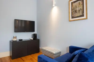 a living room with a blue couch and a flat screen tv at CASA JOY Santa Catarina apartment in Porto