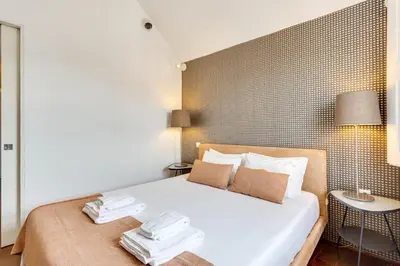 a bedroom with a white bed with a tile wall at Traça Apartments by DA'HOME in Porto