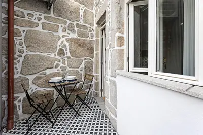 a patio with a table and chairs next to a stone wall at Cimo de Vila 62 by LovelyStay in Porto
