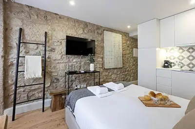 a bedroom with a white bed and a stone wall at Cimo de Vila 62 by LovelyStay in Porto