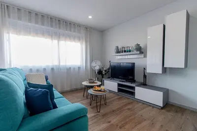 a living room with a blue couch and a television at Downtown 1BR Apartment W/ Balcony by LovelyStay in Porto