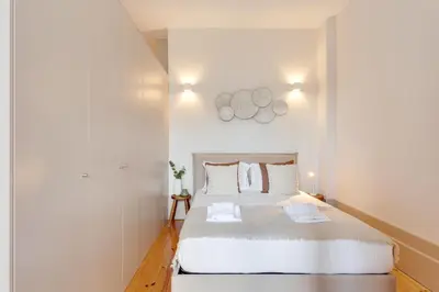 a white bedroom with a large bed with two pillows at Dom João Premium Apartment by DA'HOME in Porto