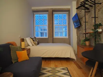 a bedroom with a bed and a couch and two windows at Casa Farrapos in Porto