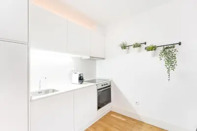 a white kitchen with white cabinets and a sink at GuestReady - Bright home in the heart of Porto in Porto