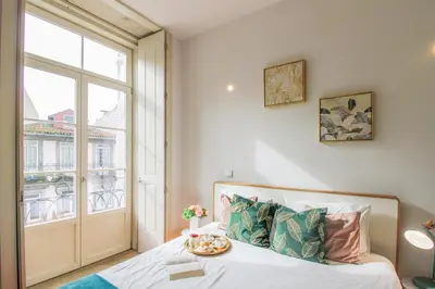 a bedroom with a bed and a large window at Aliados Sunny Flat in Porto