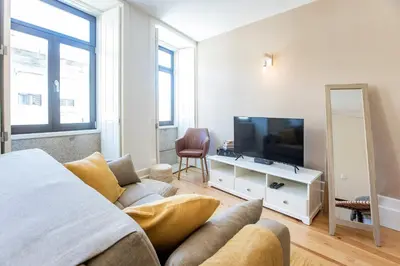 a living room with a bed and a television at Cosy Flat Near Douro in Porto