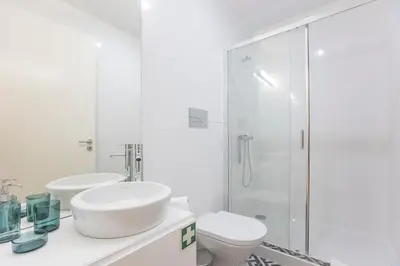 a white bathroom with a sink and a shower at Cosy Flat Near Douro in Porto