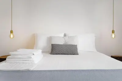a white bed with white pillows and towels on it at Aida's Haven Penthouse&Parking in Porto
