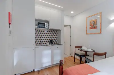 a kitchen with white cabinets and a table in a room at Cozy Studio w/ Patio by LovelyStay in Porto