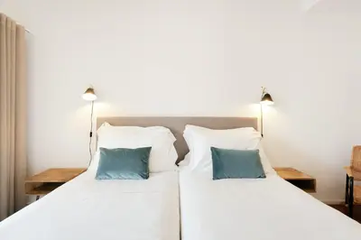 two beds in a bedroom with two blue pillows at Feel Porto Classic Apartment in Porto