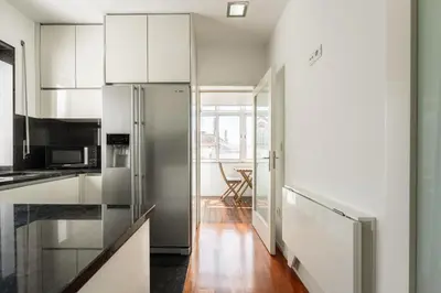 a kitchen with white cabinets and a refrigerator at Feel Porto Classic Apartment in Porto