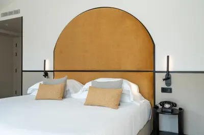 a bedroom with a white bed with a wooden headboard at The Editory Garden Porto Hotel in Porto