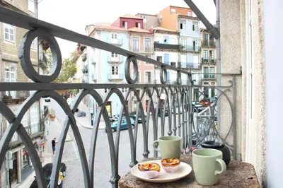 a table with two cups and a plate of food on a balcony at Virtudes Irresistible Getaway in Porto