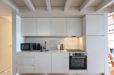 a white kitchen with white cabinets and appliances at São Bento Premium Loft - With Air Conditioning in Porto