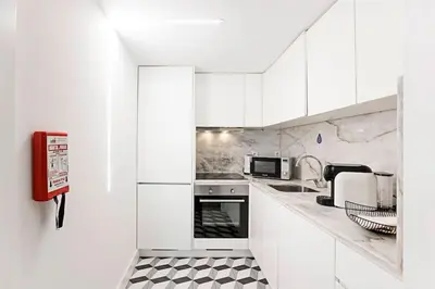 a white kitchen with a black and white checkered floor at Oporto Colorful Flat in Porto