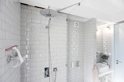 a bathroom with a shower with a white tile wall at O Aleph, irresistible duplex apt. w/AC and balcony in Porto