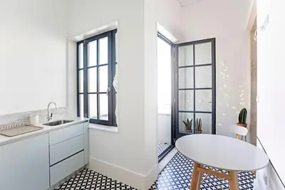 a white kitchen with a table and some windows at O Aleph, irresistible duplex apt. w/AC and balcony in Porto