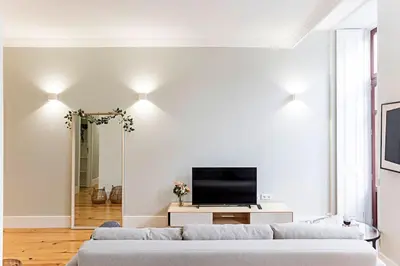 a white living room with a couch and a tv at Historical Sunny Marquês - With AC! in Porto