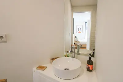 a white bathroom with a sink and a mirror at Porto Trindade Triplex in Porto