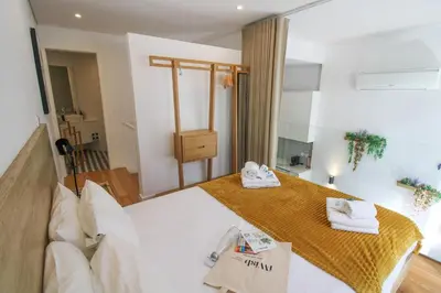 a bedroom with a large white bed and a mirror at Porto Trindade Triplex in Porto