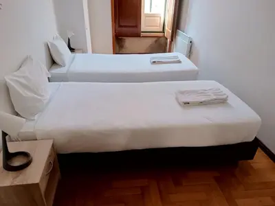 two beds in a small room with a window at Flores Apartment in Porto