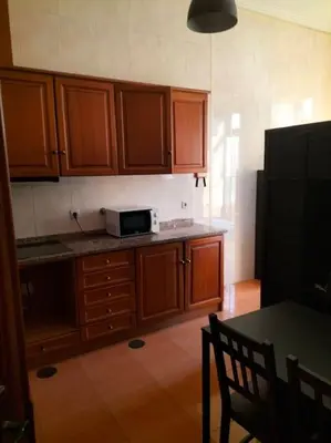 a kitchen with wooden cabinets and a black microwave at Flores Apartment in Porto