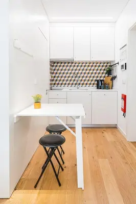 a white kitchen with a white table and two stools at GuestReady - Studio in Porto in Porto