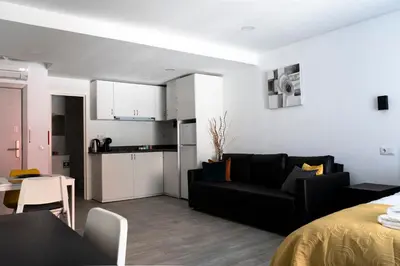 a living room with a black couch and a kitchen at Almada Downtown 203 in Porto