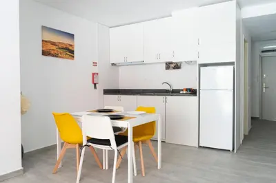 a kitchen with a white table and yellow chairs at Almada Downtown 204 in Porto