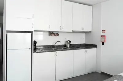 a white kitchen with a sink and a refrigerator at Almada Downtown 301 in Porto