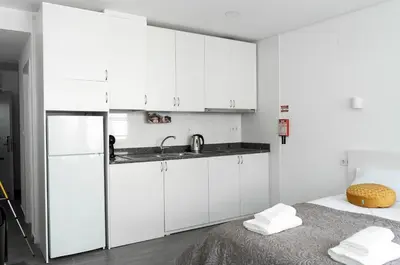 a kitchen with white cabinets and a sink and a bed at Almada Downtown 301 in Porto