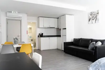 a living room with a black couch and a kitchen at Almada Downtown 303 in Porto