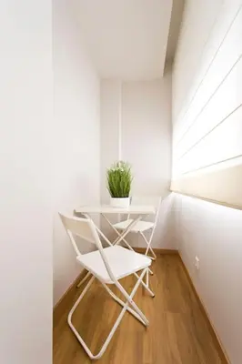 a white chair and a table in a room with a window at APOSENTUS - Marta's House in Porto