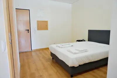 a bedroom with a bed with white sheets and a wooden floor at Tomás Flat in Porto