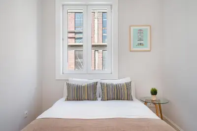 a white bedroom with a bed and a window at Whome Formosa #2 - Central 2-Bed in Prime Location Perfect to Explore Porto in Porto