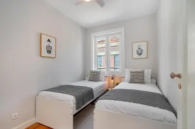 two beds in a room with white walls and windows at Whome Formosa #3 - Central 2-Bed in Prime Location Perfect to Explore Porto in Porto