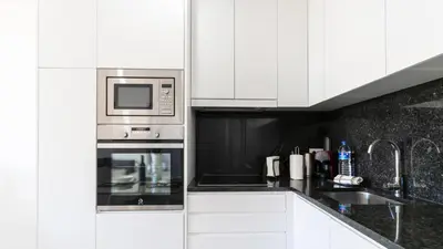 a kitchen with white cabinets and a microwave at Delightful Bombarda Apartment by Unique Hosts in Porto