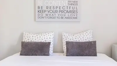 a bed with two pillows and a sign on the wall at Delightful Bombarda Apartment by Unique Hosts in Porto