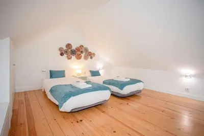 two beds in a white room with wooden floors at Liiiving in Porto - Heart of Porto Mezzanine in Porto