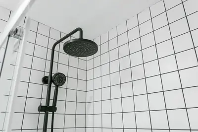 a shower with a light on a white tiled wall at GuestReady - Uptown suites in Porto