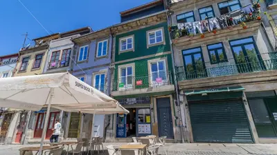 an umbrella and tables in front of a building at Aposentus - Stylish Downtown Loft in Porto