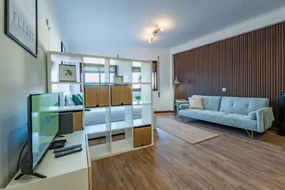 a room with a bed and a kitchen with a red stool at Plan C Downtown Apartment in Porto