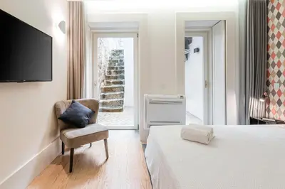 a bedroom with a bed and a chair and a television at Door 65 - Historical Center Apartments in Porto