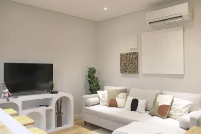 a living room with a white couch and a flat screen tv at Artistic Neighborhood Luxury in Porto