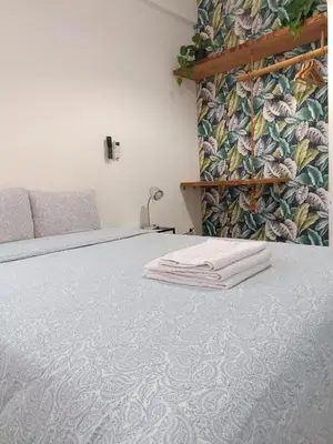 a bedroom with a bed with white sheets and a wall at Porto Grand Sasimi House in Porto